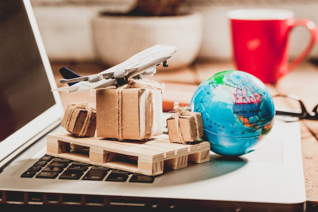 Primer plano de un modelo de avión con cajas, un globo terráqueo y un ordenador portátil