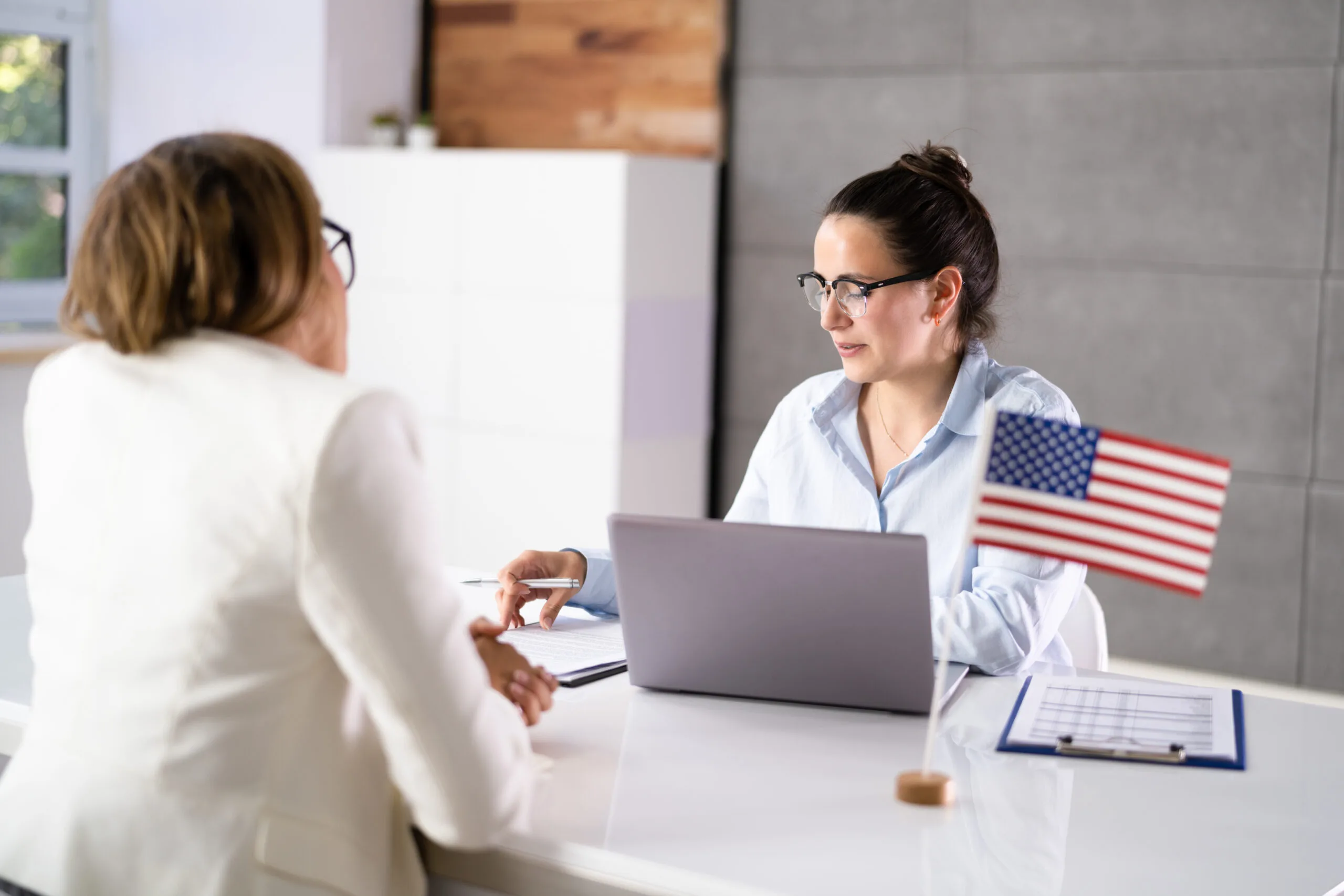 An employee applying for an American visa with a US flag on the table.