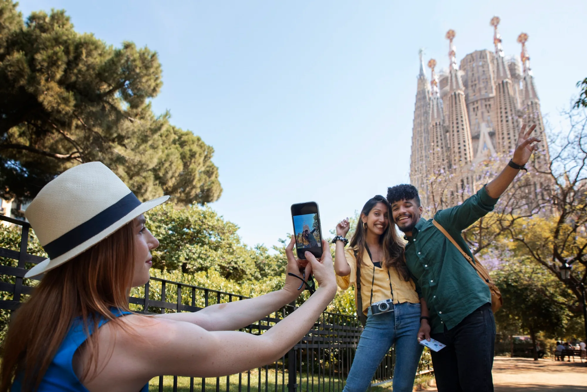 Tourists in front of the Sagrada Familia in Barcelona, taking photos to record their trip to Spain