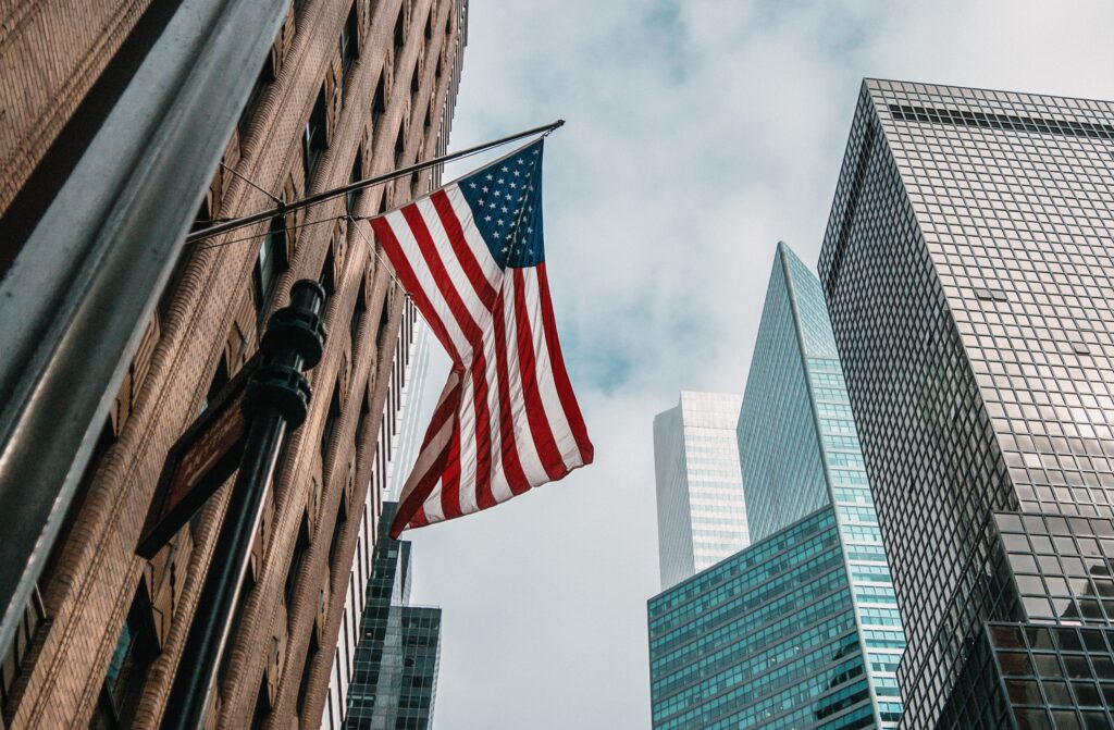 Usa united states america flag flagpole near skyscrapers cloudy sky