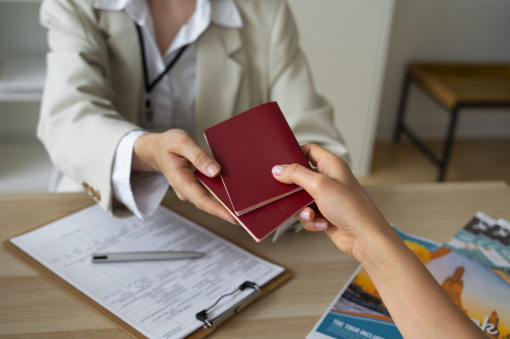 Front view woman working as a travel agent Travel agent handing out red passports on table with forms